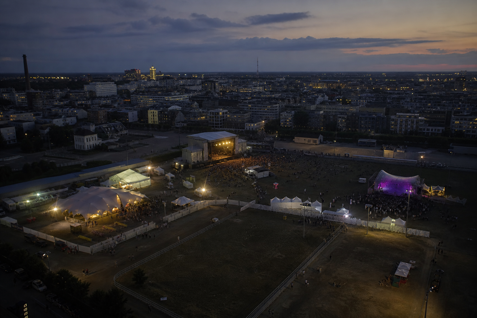 Historisches Festivalgelände mit mehreren getrennten Veranstaltungsbereichen bei Dämmerung